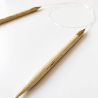 Bildet viser en strikkepinne i tre som ligger flatt på et bord. Leveramdøre er Skappelstrikk.